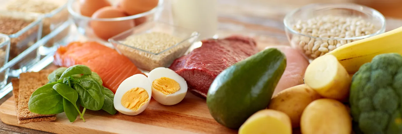 A spread of protein and fibre foods together on a board: salmon, eggs, avocado, broccoli, oats and pulses.